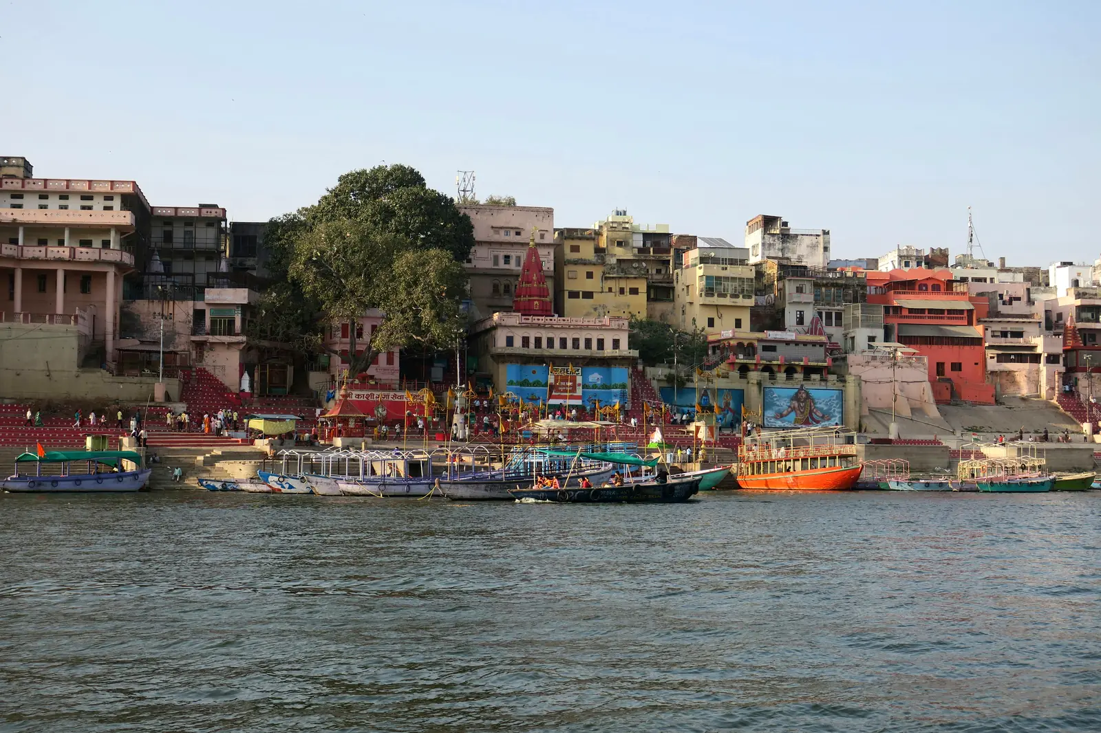 Varanasi ghats on the Ganga with moored boats and temple spire at sunrise